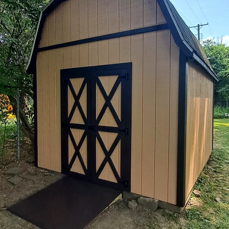 Custom tan barn-style shed with dark cross-braced double doors
